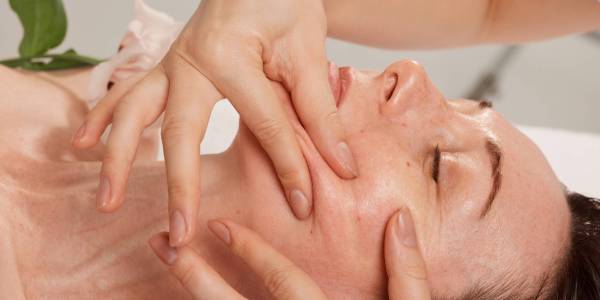 cosmetologist doing facial massage to a girl in a beauty salon, beauty procedures for smoothing the skin